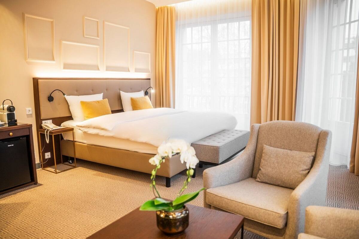 A hotel room with a bed, bedside table, chair, and a small desk with a telephone.