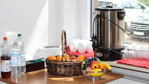 Un plateau de petit-déjeuner comprenant un grille-pain, des bouteilles d’eau, un panier de fruits et une machine à café.