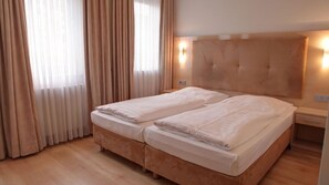 A double bed with a wooden headboard, a bedside table, and a nightstand.