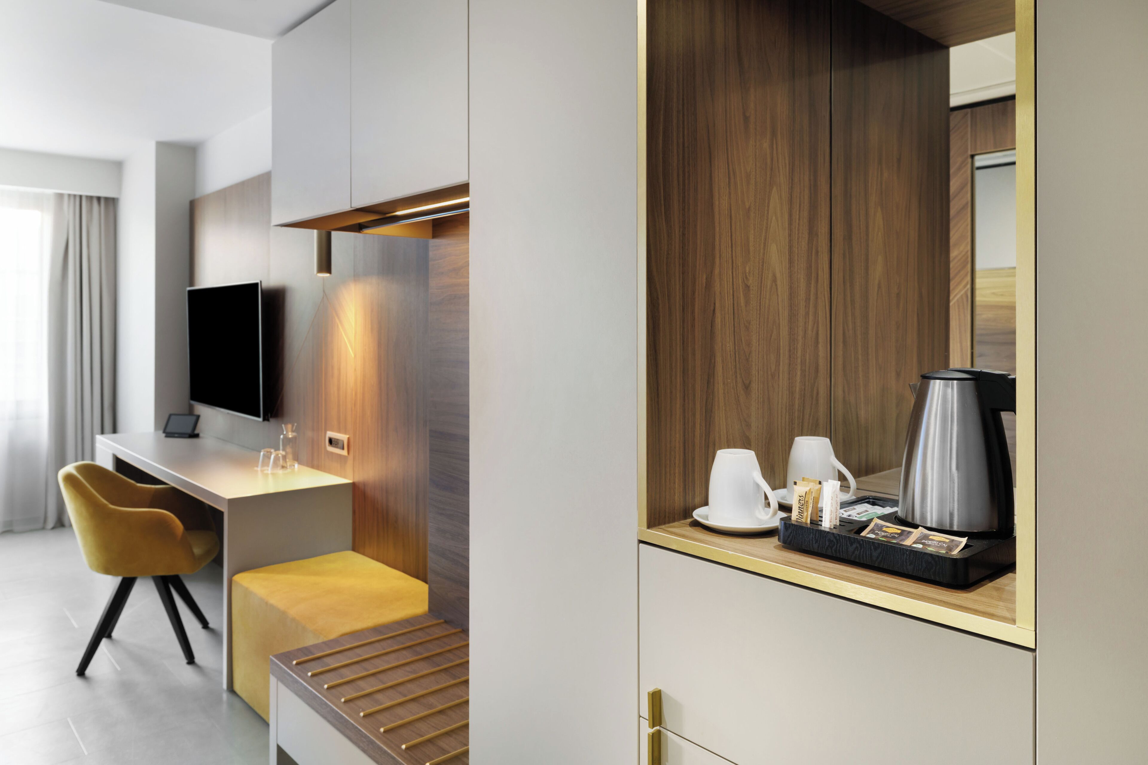 Habitació d'hotel moderna amb escriptori, televisió, zona de cafè i una paret decorativa de fusta.