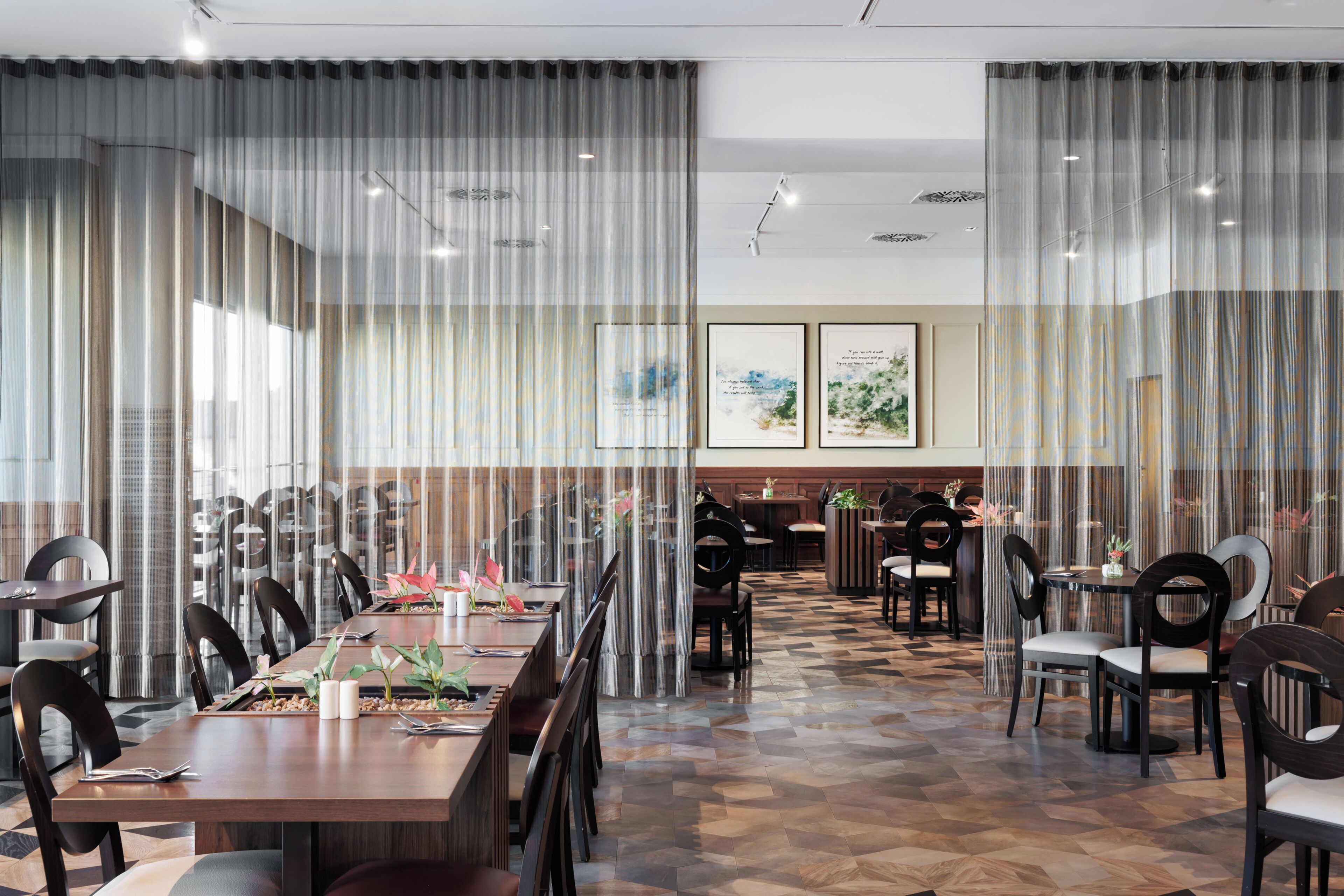 Un espace de restauration moderne avec une longue table, des chaises et un sol à motifs.
