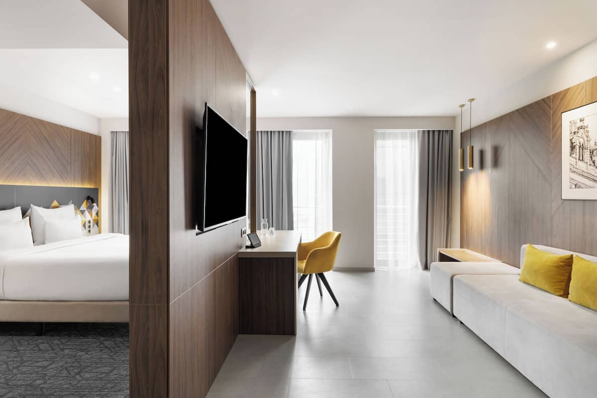 Ein modernes Hotelzimmer mit Bett, Schreibtisch, Sofa und Fernseher.