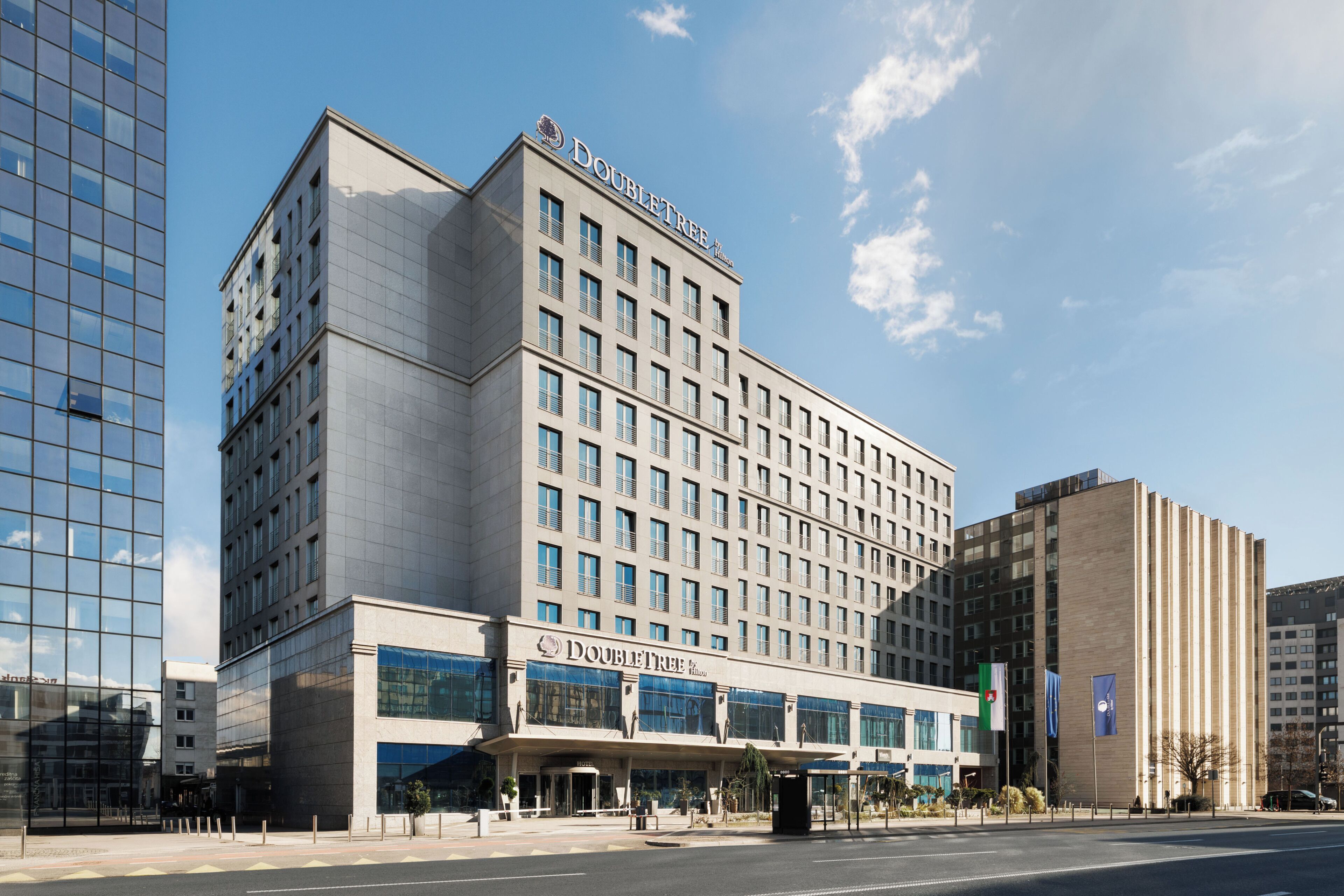 A DoubleTree hotel with a modern glass facade, a prominent entrance, and a clear sky.