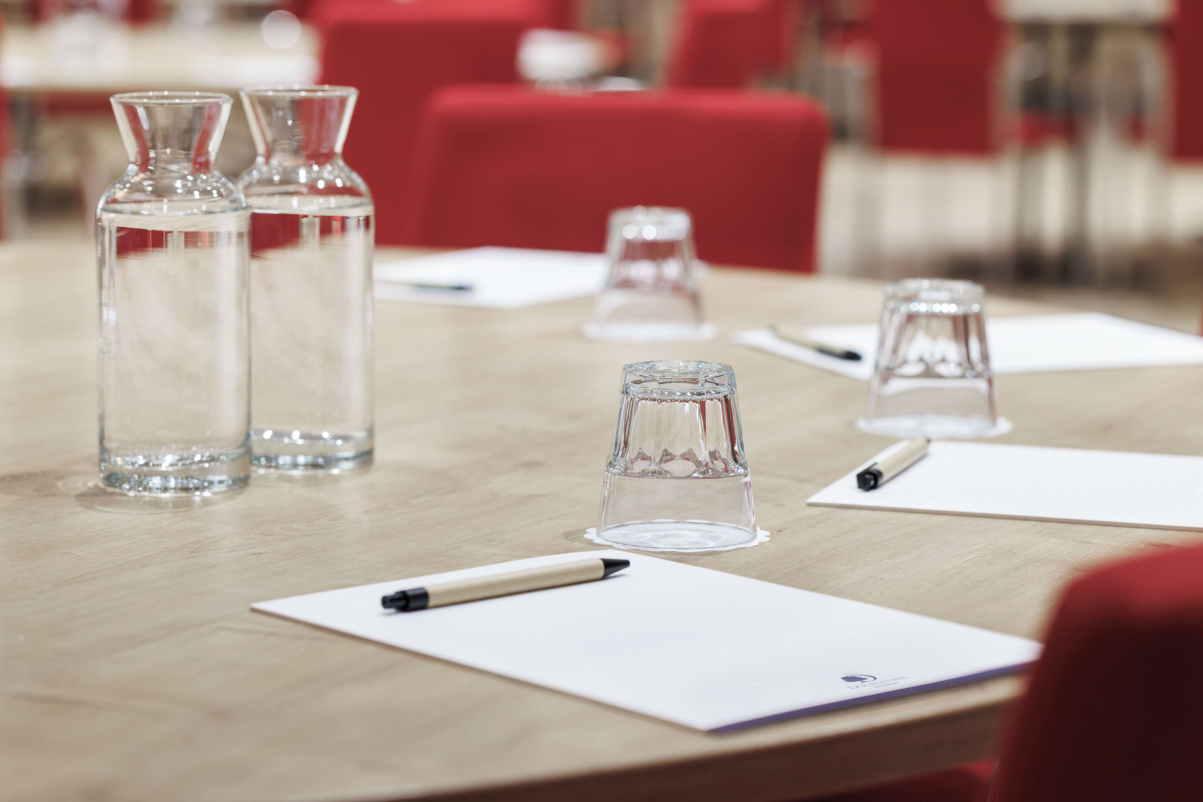 Ein Konferenztisch mit Wasserflaschen, Gläsern und Notizblöcken.