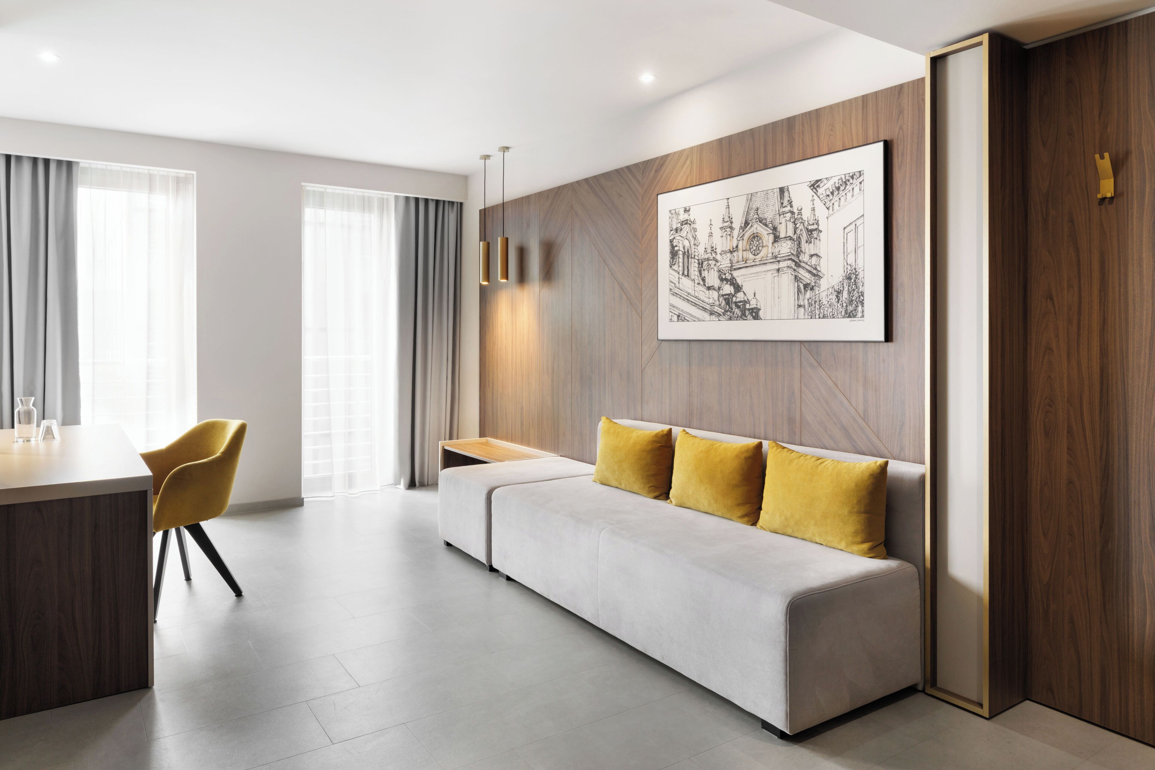 A modern hotel room with a sofa, a dining table, and a framed picture on the wall.
