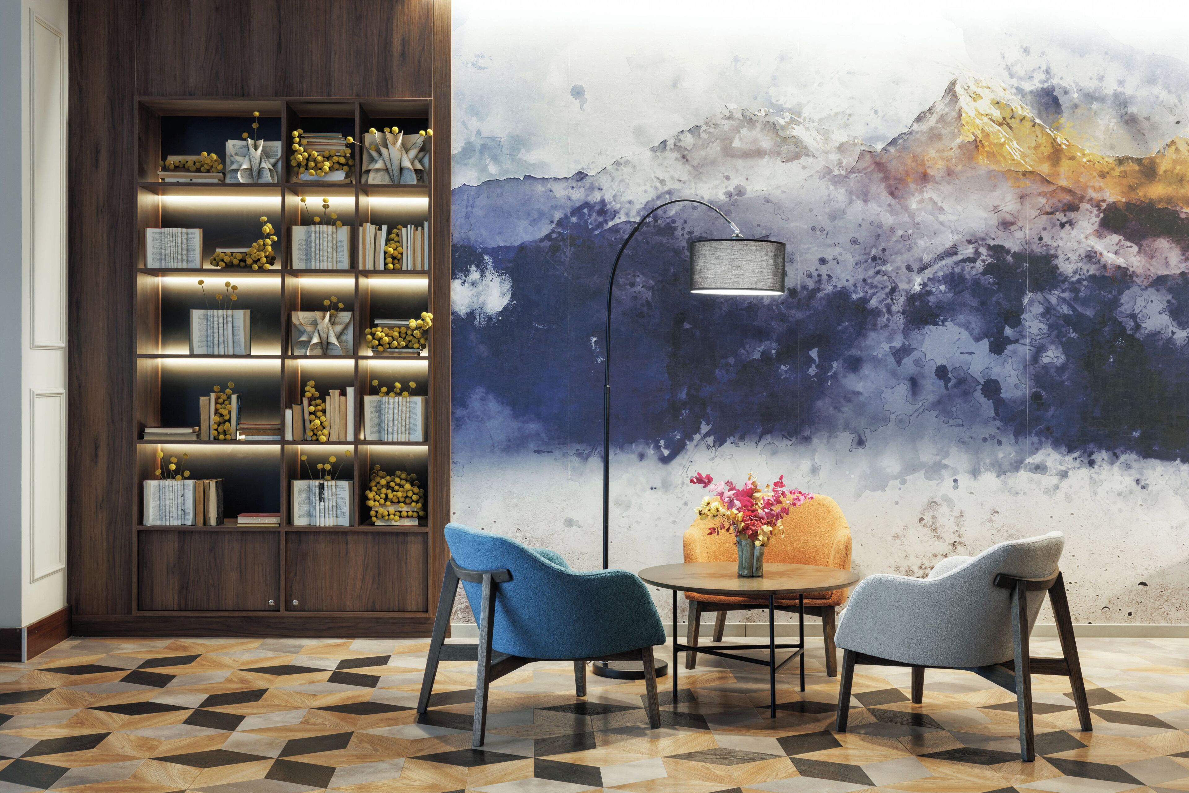 A room with a geometric patterned floor, a wooden bookshelf with decorative items, a round table with two chairs, and a wall with a mountain painting.
