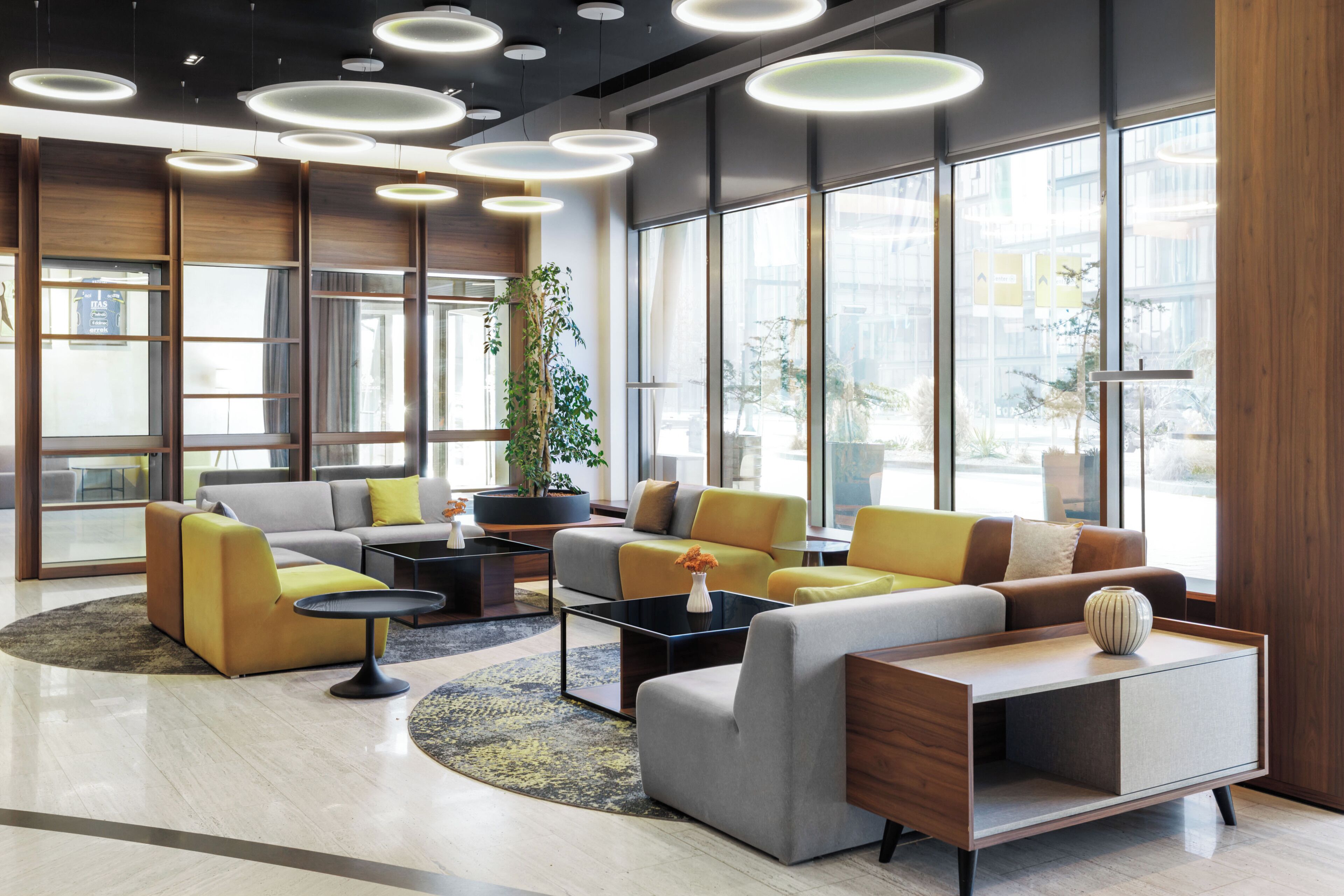 A modern lobby with a sofa, coffee table, and a potted plant.