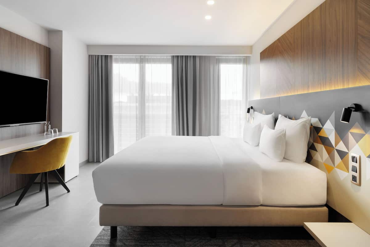 Ein modernes Hotelzimmer mit einem großen Bett, einem Schreibtisch und einem Fernseher.