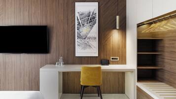 Una habitación de hotel moderna con una pared de madera, un televisor de pantalla plana, un escritorio con una silla y un armario con espacio para colgar.