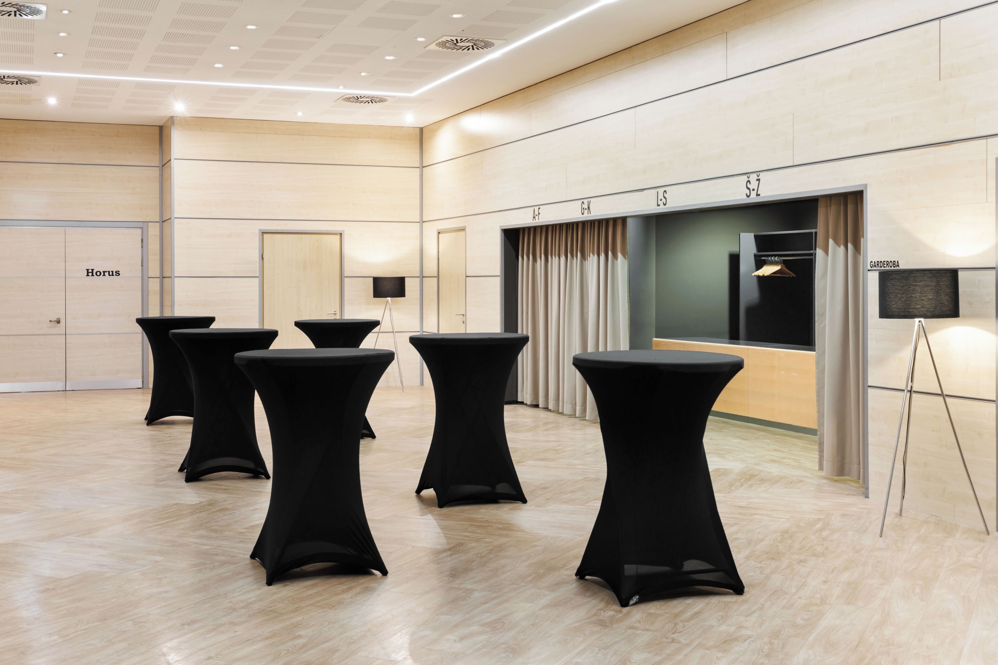 A spacious room with black tables, a large mirror, and a 'GARDEROB' sign.