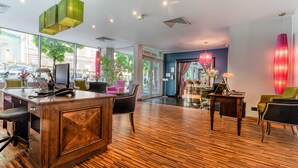 A modern hotel lobby with a wooden reception desk, comfortable seating, large windows, and stylish lighting fixtures. - Don Prestige Residence (Poznan)