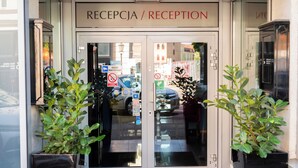 A hotel reception with a sign reading "RECEPTION" and a "No Parking" sign visible through the glass doors. - Don Prestige Residence (Poznan)