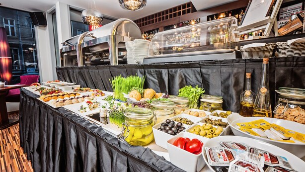 A buffet setup with various food items, including salads, breads, and condiments, arranged on a table with a black tablecloth. - Don Prestige Residence (Poznan)
