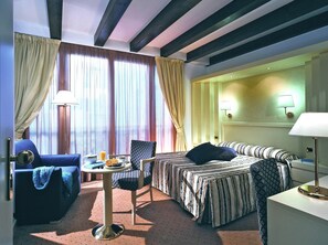 Relax in this stylish room with a large bed, sofa, and table, perfect for unwinding.