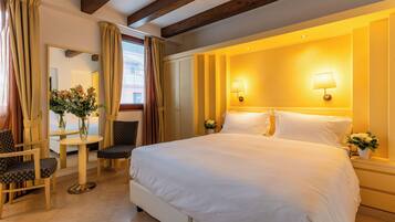 A hotel room with a large bed, two bedside lamps, a small table with chairs, and a mirror.