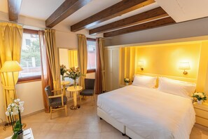 A hotel room with a bed, two chairs, a small table, and a window with curtains. - Hotel Giudecca Venezia (Venice)