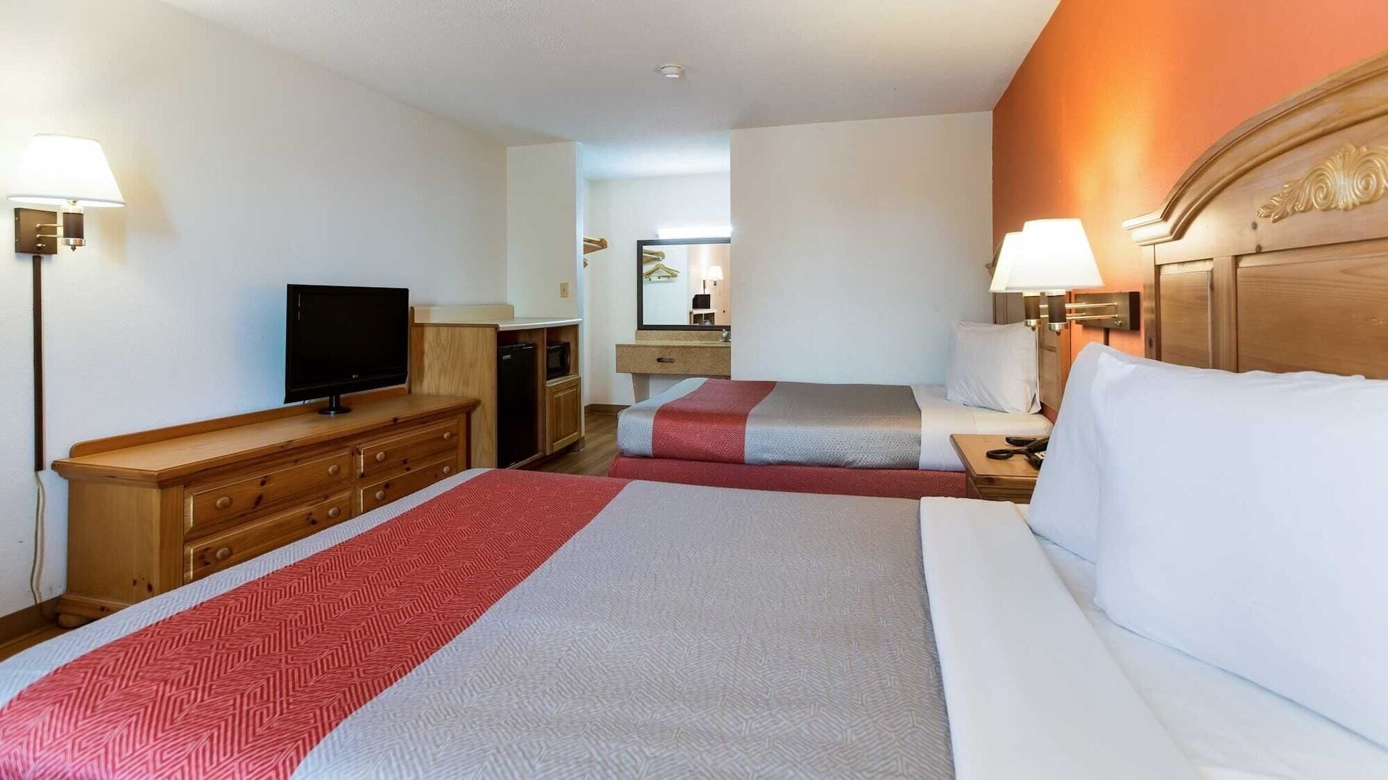 Une chambre d’hôtel avec deux lits, une télévision, une commode et un miroir.