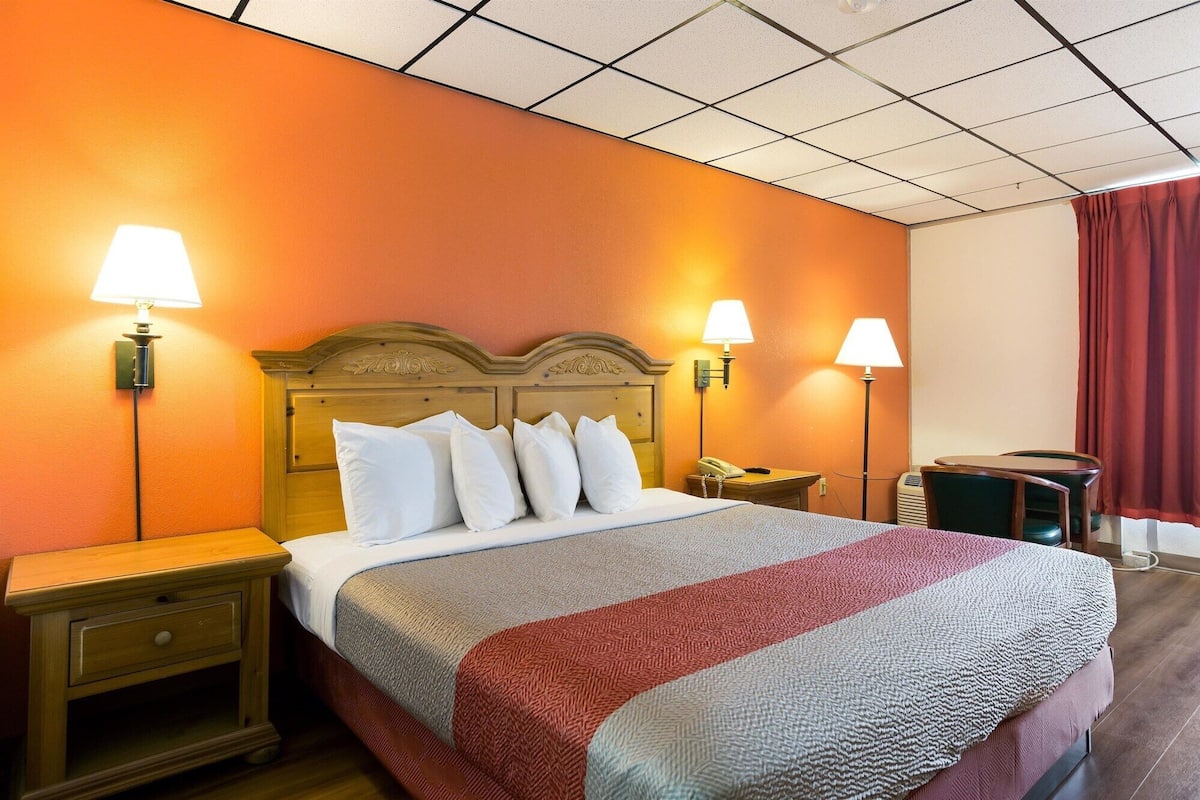 Una habitación de hotel con una cama grande, dos mesitas de noche, un escritorio y una silla.