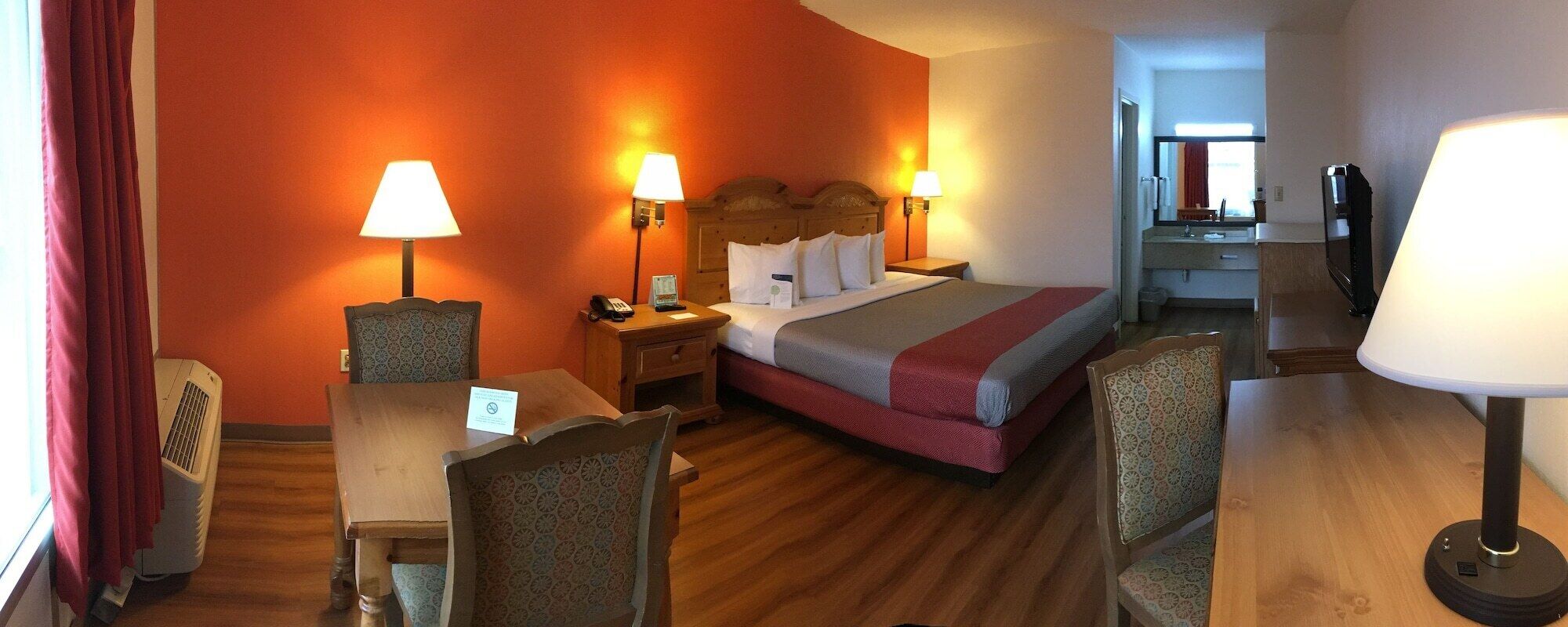 Habitación de hotel con cama, dos mesitas de noche, dos lámparas, un escritorio y dos sillas.