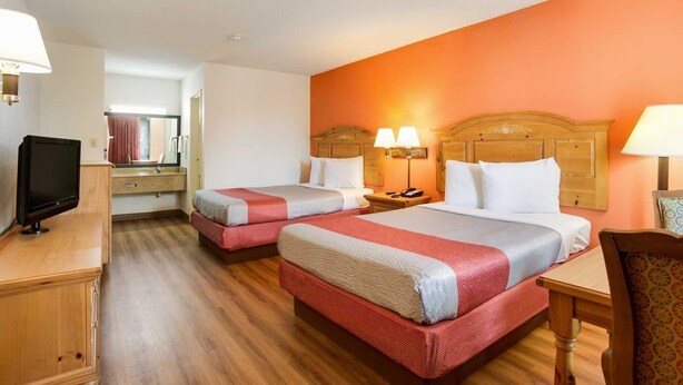 Habitación de hotel con dos camas, un televisor, un escritorio y una silla.