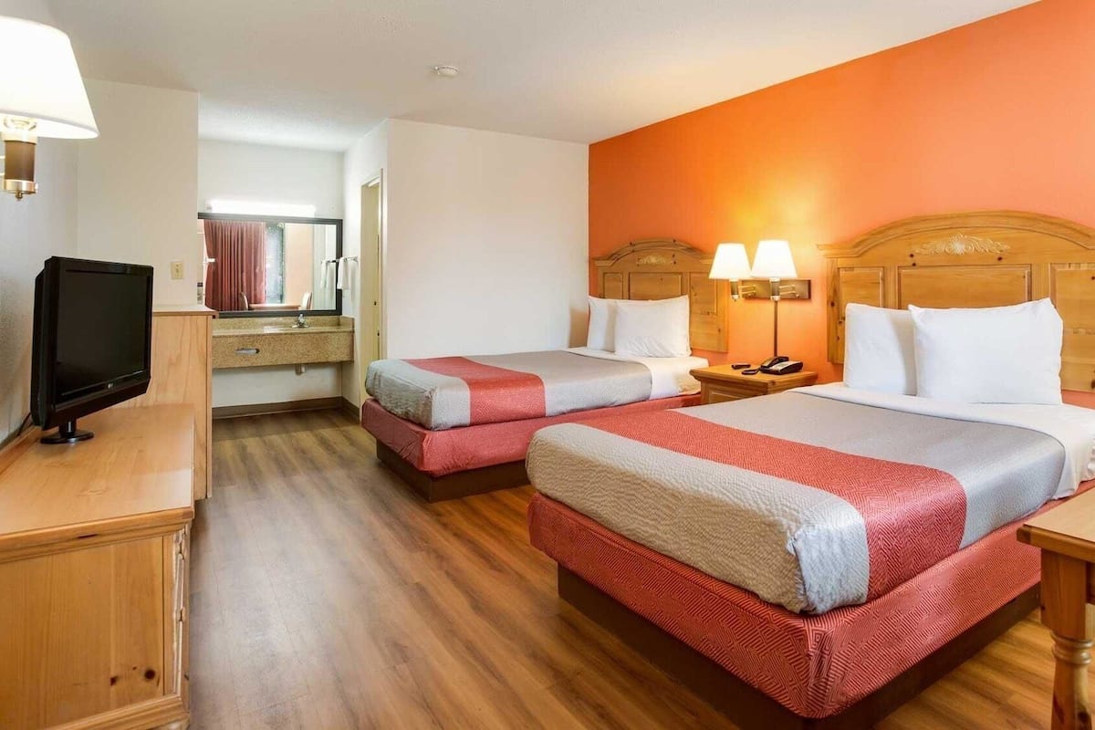 Una habitación de hotel con dos camas, un televisor, un escritorio y una silla.