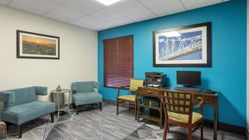 A room with a blue accent wall, a desk with a computer, two chairs, a sofa, and a small table with a plant.