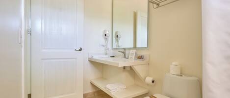 A bathroom with a white door, a sink with a mirror above it, a toilet with a towel on the seat, and a towel rack with towels.