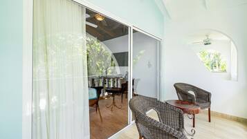A room with a dining area, wicker chairs, a table, and a view through a glass door.
