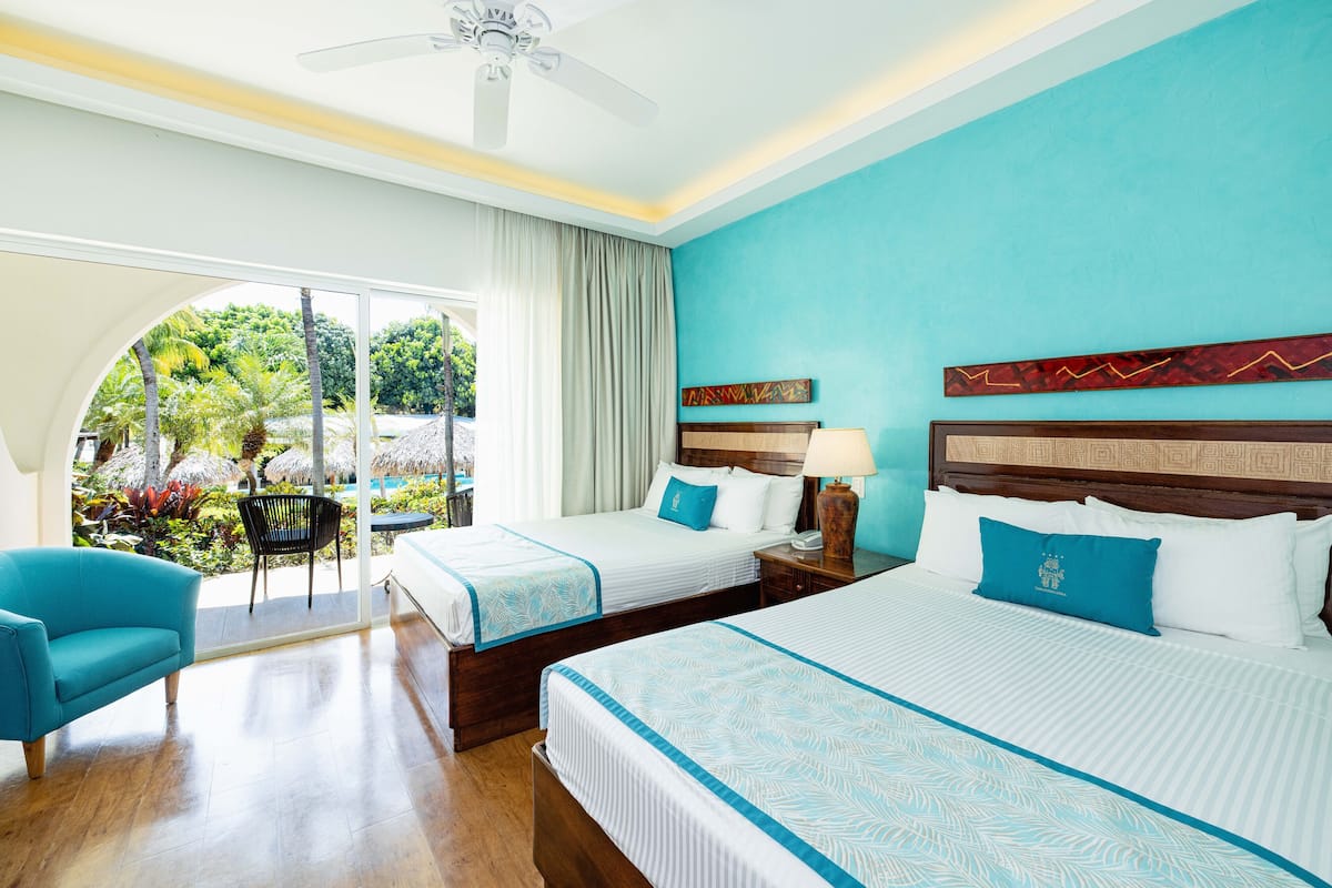 Une chambre d’hôtel avec deux lits, un canapé, un ventilateur de plafond et une vue sur l’extérieur.