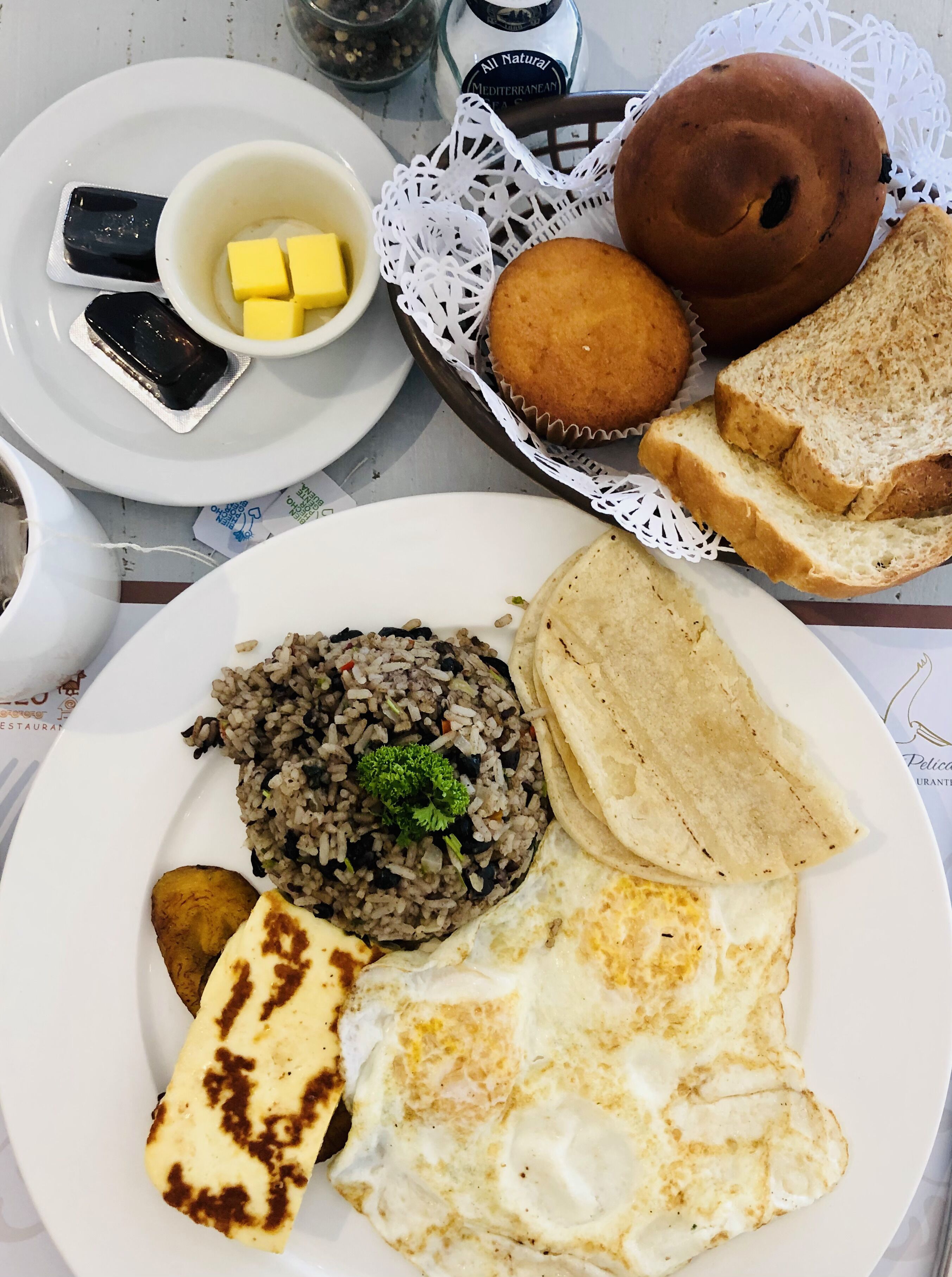A plate with rice, fried egg, plantain, and bread.