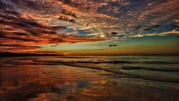 Ein Strand mit Sonnenuntergang und ruhigem Wasser.