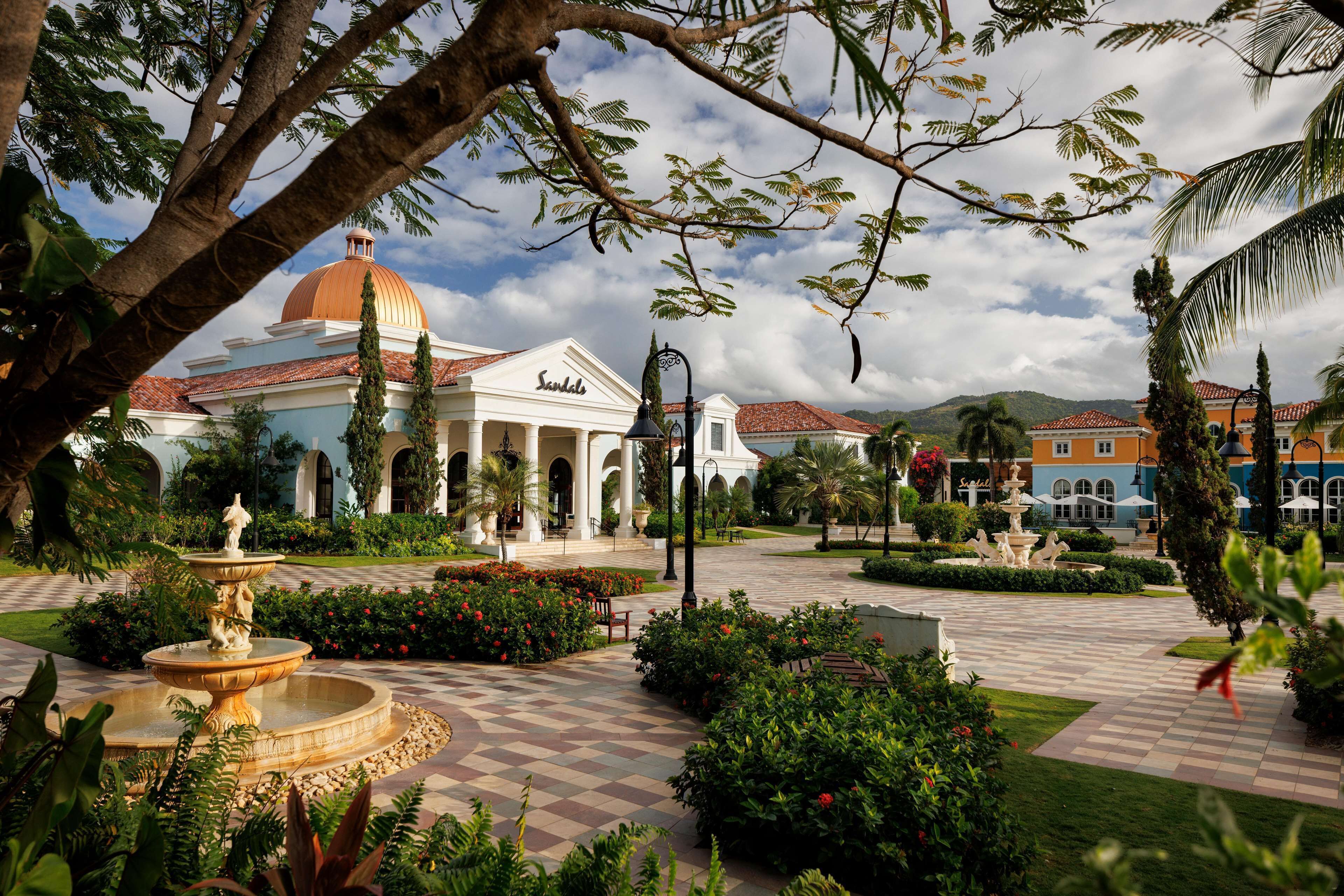 A courtyard with a fountain, palm trees, and a building with a dome.