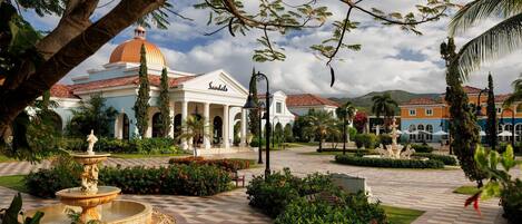 A courtyard with a fountain, palm trees, and a building with a dome.
