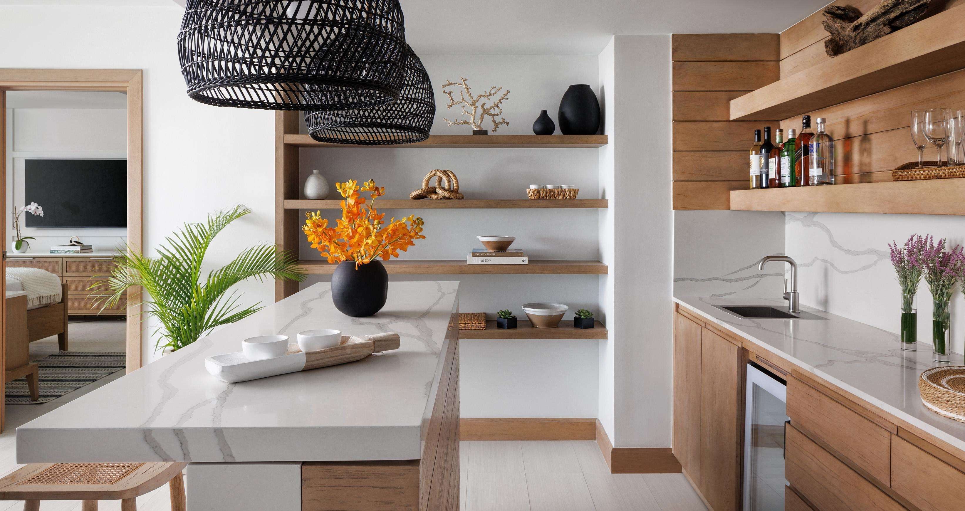 A modern kitchen with a marble countertop, wooden shelves, and a black hanging light fixture.