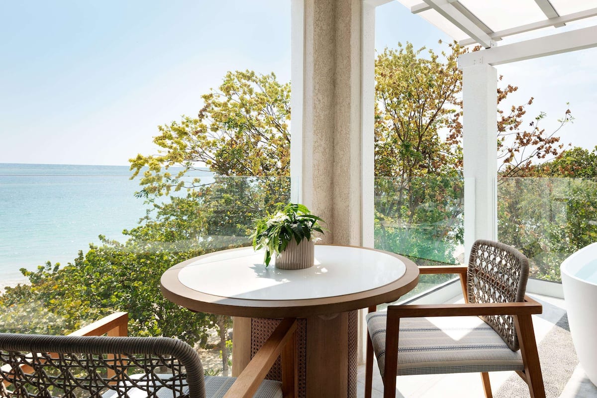 Een balkon met een ronde tafel, een stoel, een bloempot en een bad.