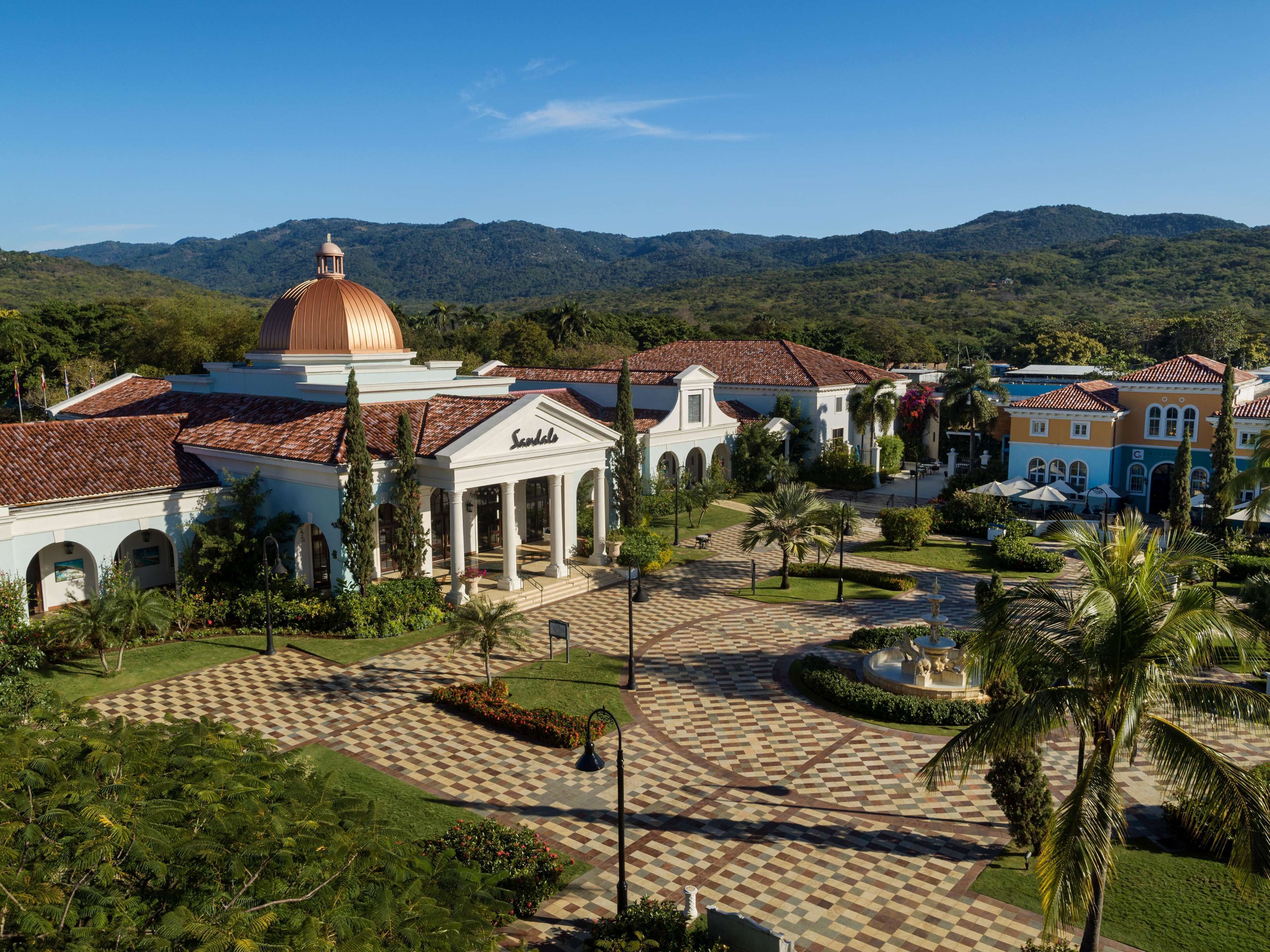 A historic building with a dome and a courtyard with palm trees and a fountain.