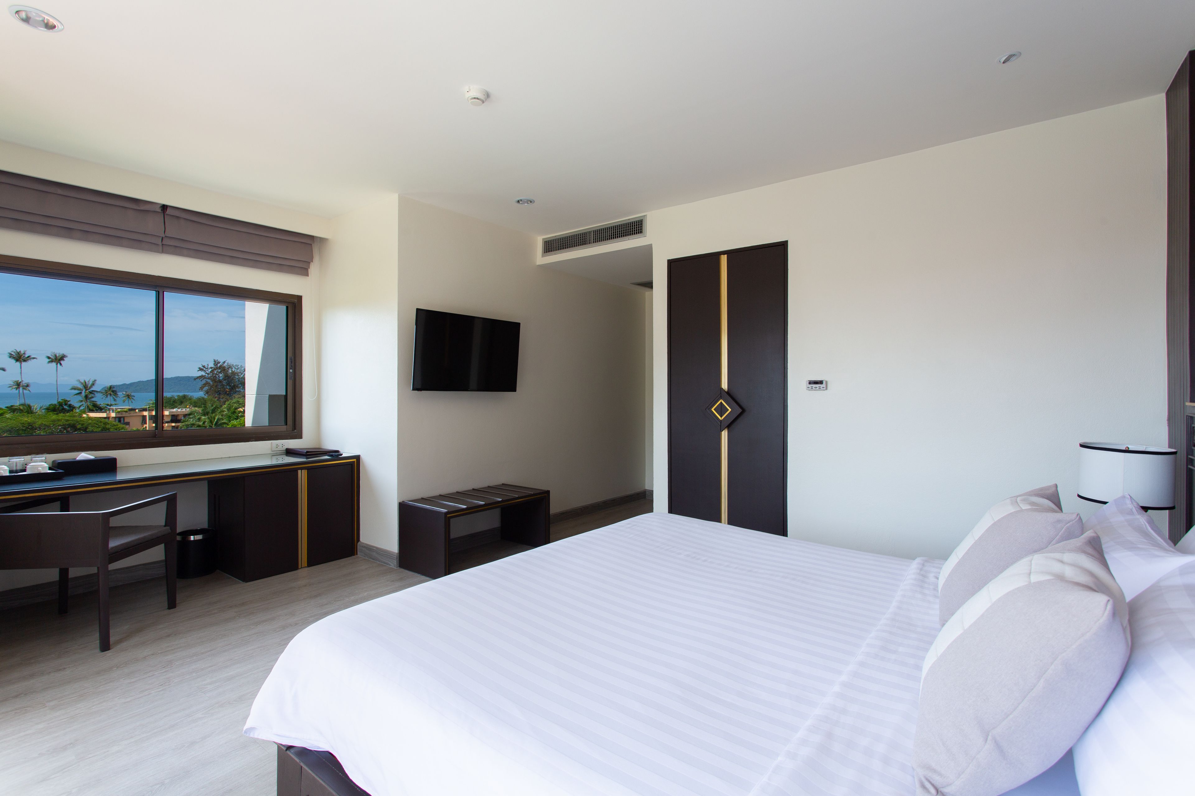 A modern hotel room with a large bed, a desk, and a TV.