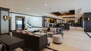 A modern hotel lobby with a reception desk, seating area, and a staircase leading to another floor. - Krabi Heritage Hotel (Krabi)