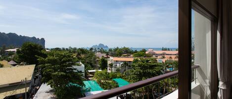 A balcony with a view of a coastal town, buildings, and mountains.