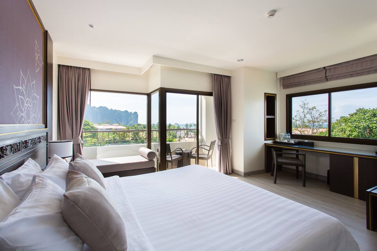 Ein Hotelzimmer mit einem großen Bett, einem Schreibtisch und Blick auf die Berge.