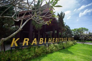 Exterior del Krabi Heritage Hotel, con un cartel llamativo, exuberante vegetación y un estilo arquitectónico tradicional.
