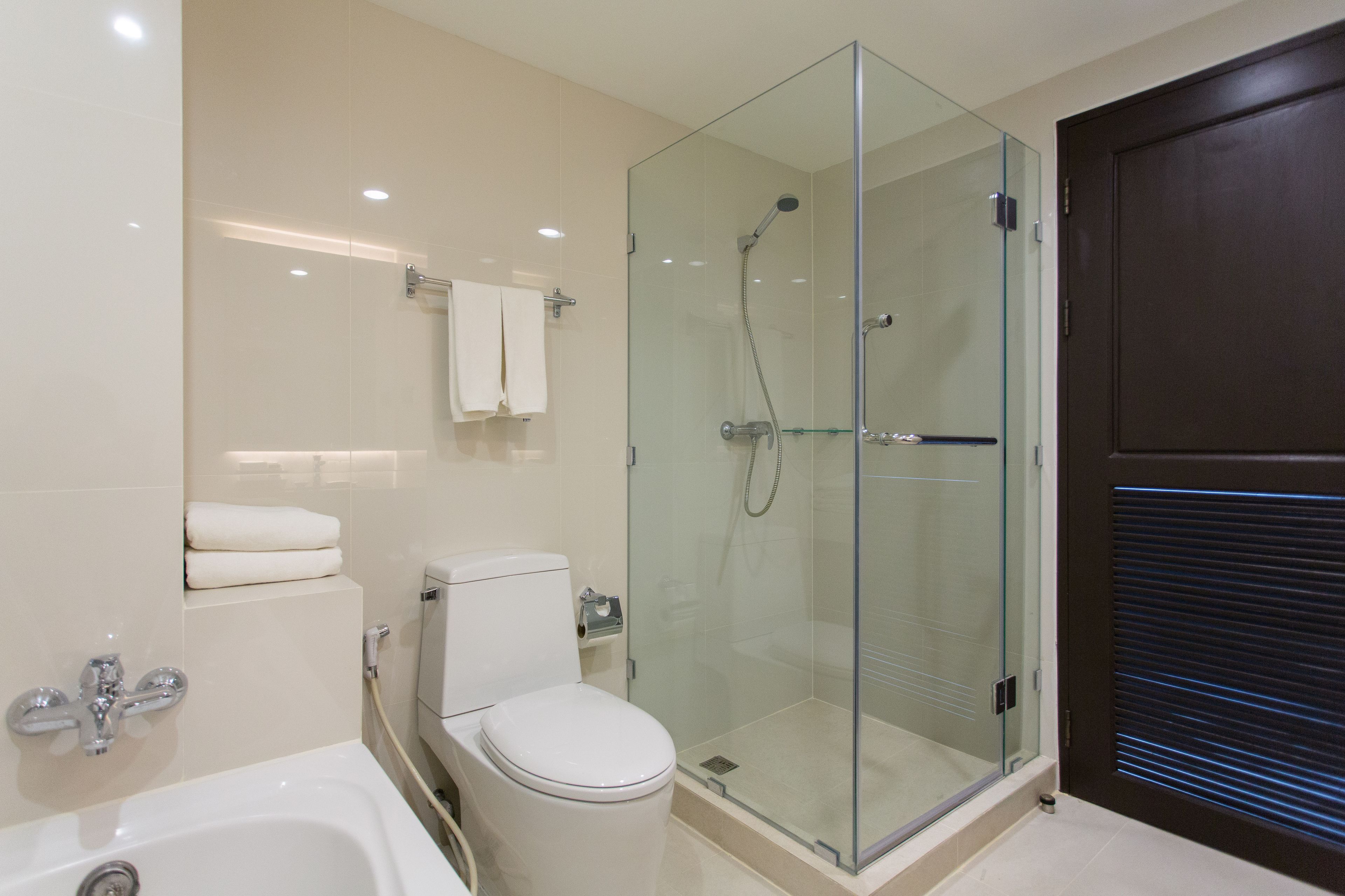 A modern bathroom with a glass-enclosed shower, a white toilet, and a bathtub.