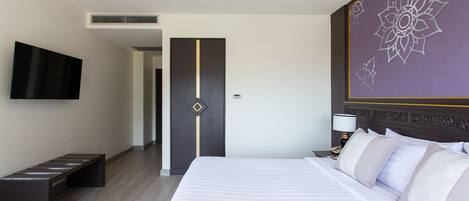Ein Hotelzimmer mit einem großen Bett, einem flachbildfernseher an der Wand, einer Bank und einer dekorativen Wandverkleidung.