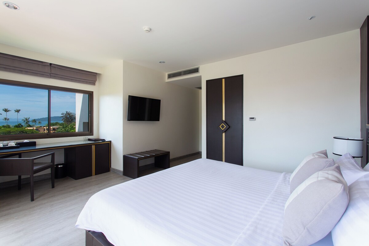 Ein modernes Hotelzimmer mit einem großen Bett, einem Schreibtisch und einem Fernseher.