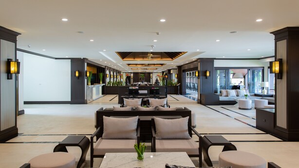 A modern hotel lobby with a central seating area, a reception desk, and a view of the outdoor seating area. - Krabi Heritage Hotel (Krabi)