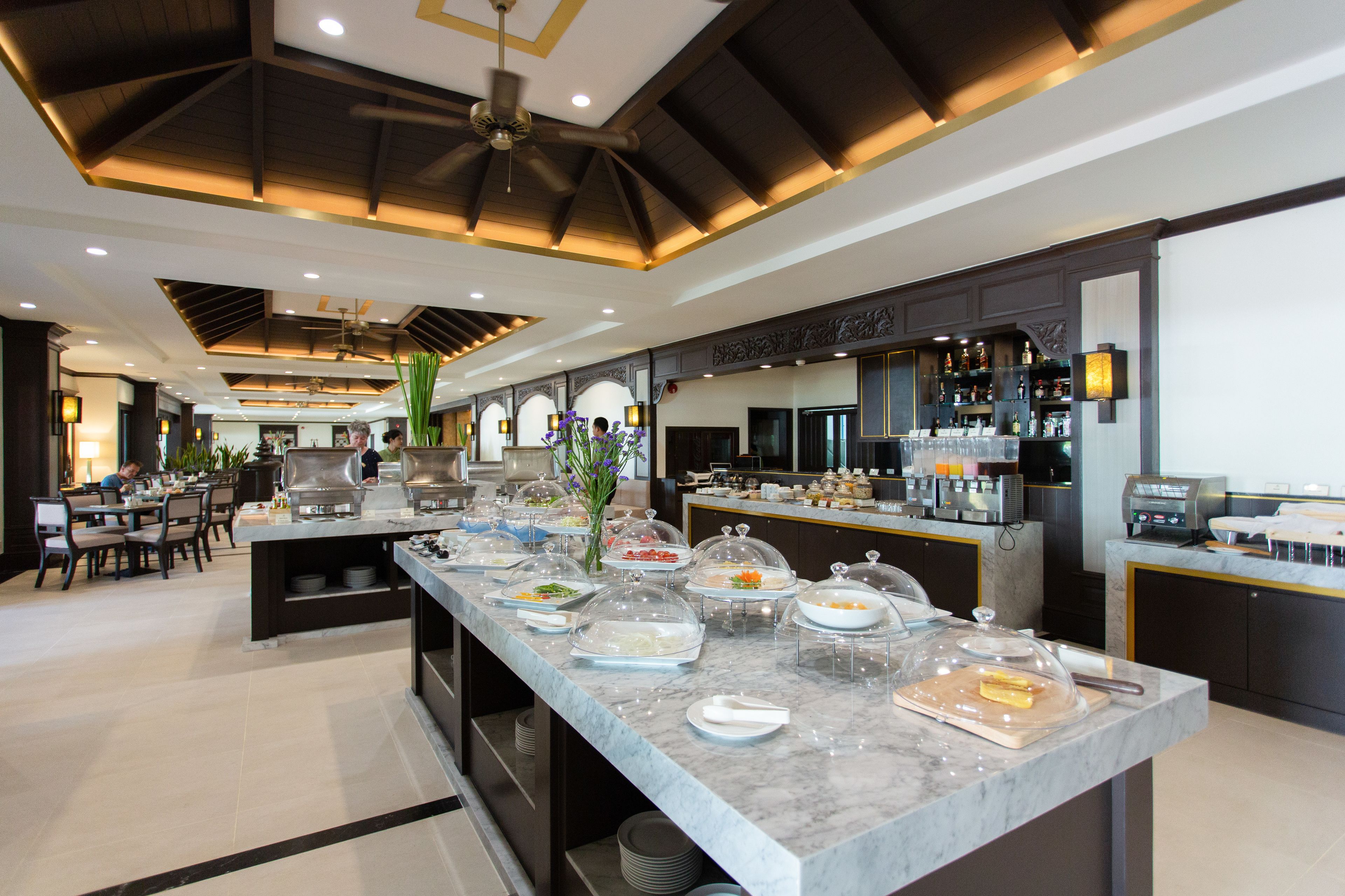 Montaje de bufé con diferentes opciones de comida y una zona de bar con bebidas.