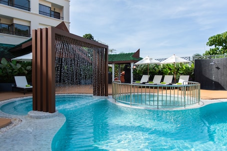 Una piscina al aire libre, sombrillas, sillones reclinables de piscina