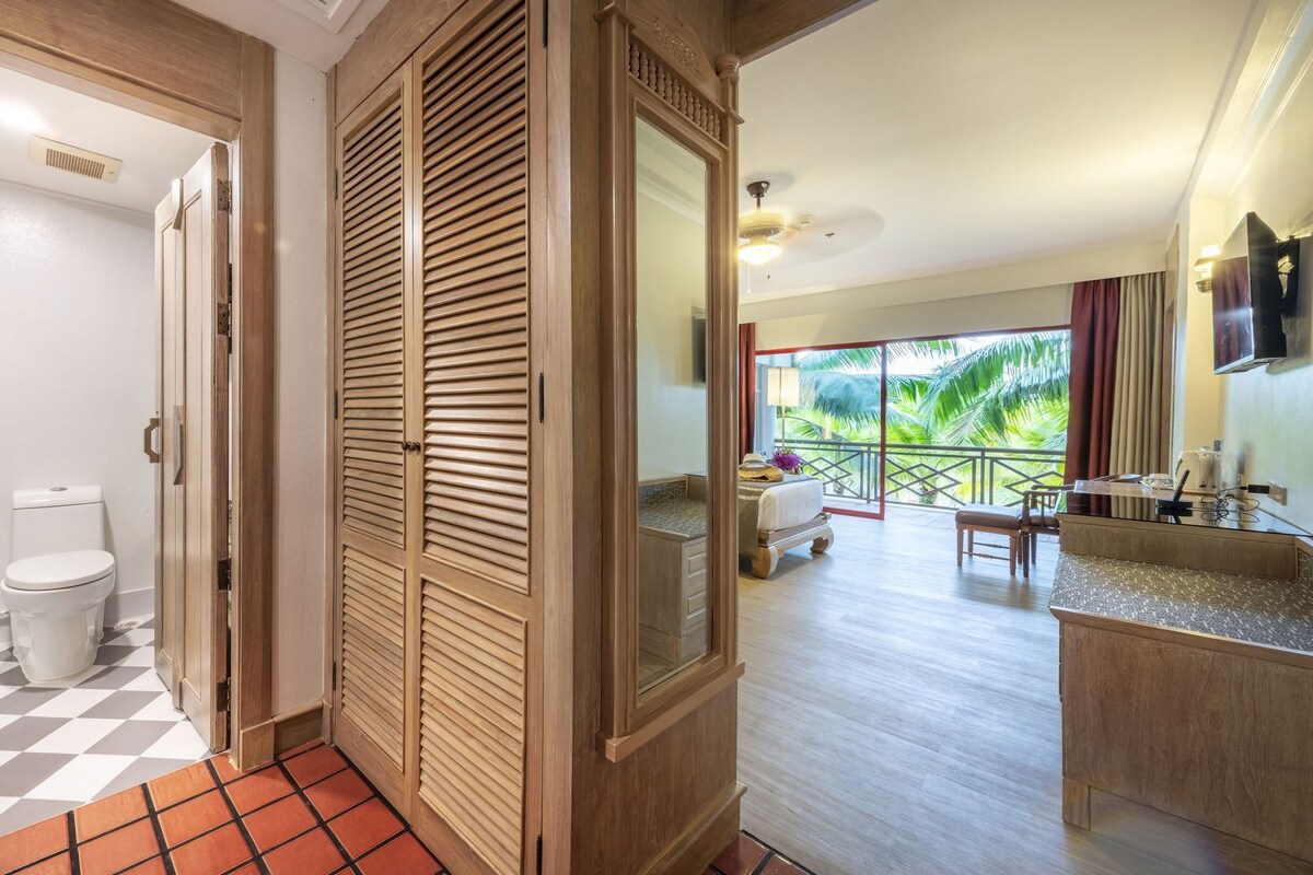 Habitación de hotel con balcón, baño con inodoro y ducha, y kitchenette.