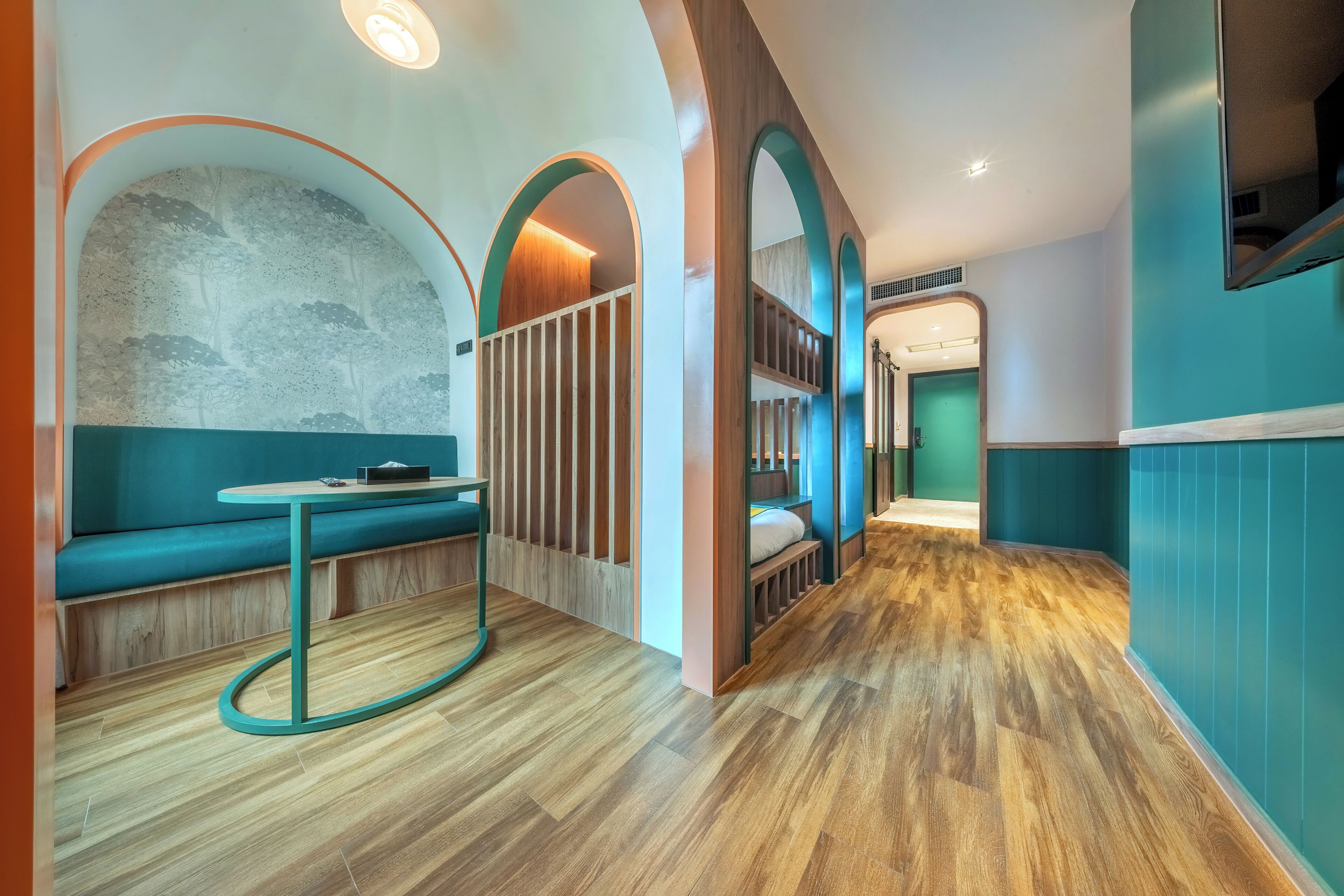 Ein modernes Interieur mit Holzboden, wandfarben in Türkis und einer Sitzecke mit einer Bank und einem Tisch.
