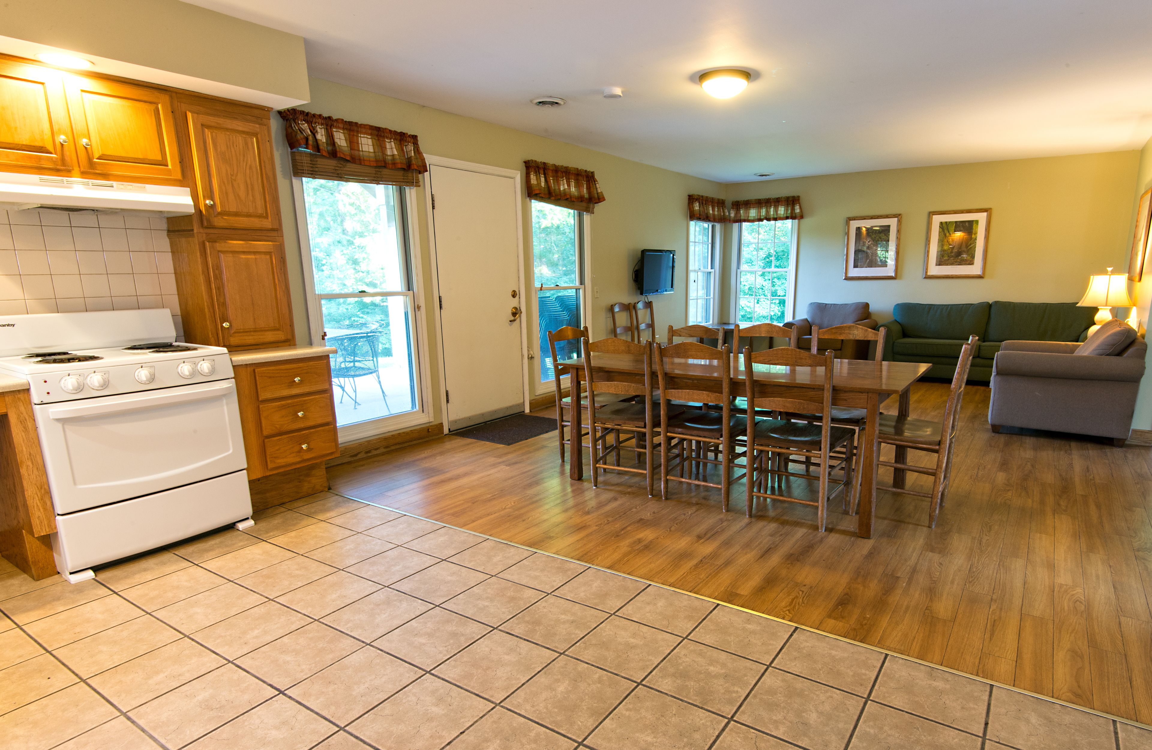 A kitchen with wooden cabinets, a white stove, and a dining area with a table and chairs.